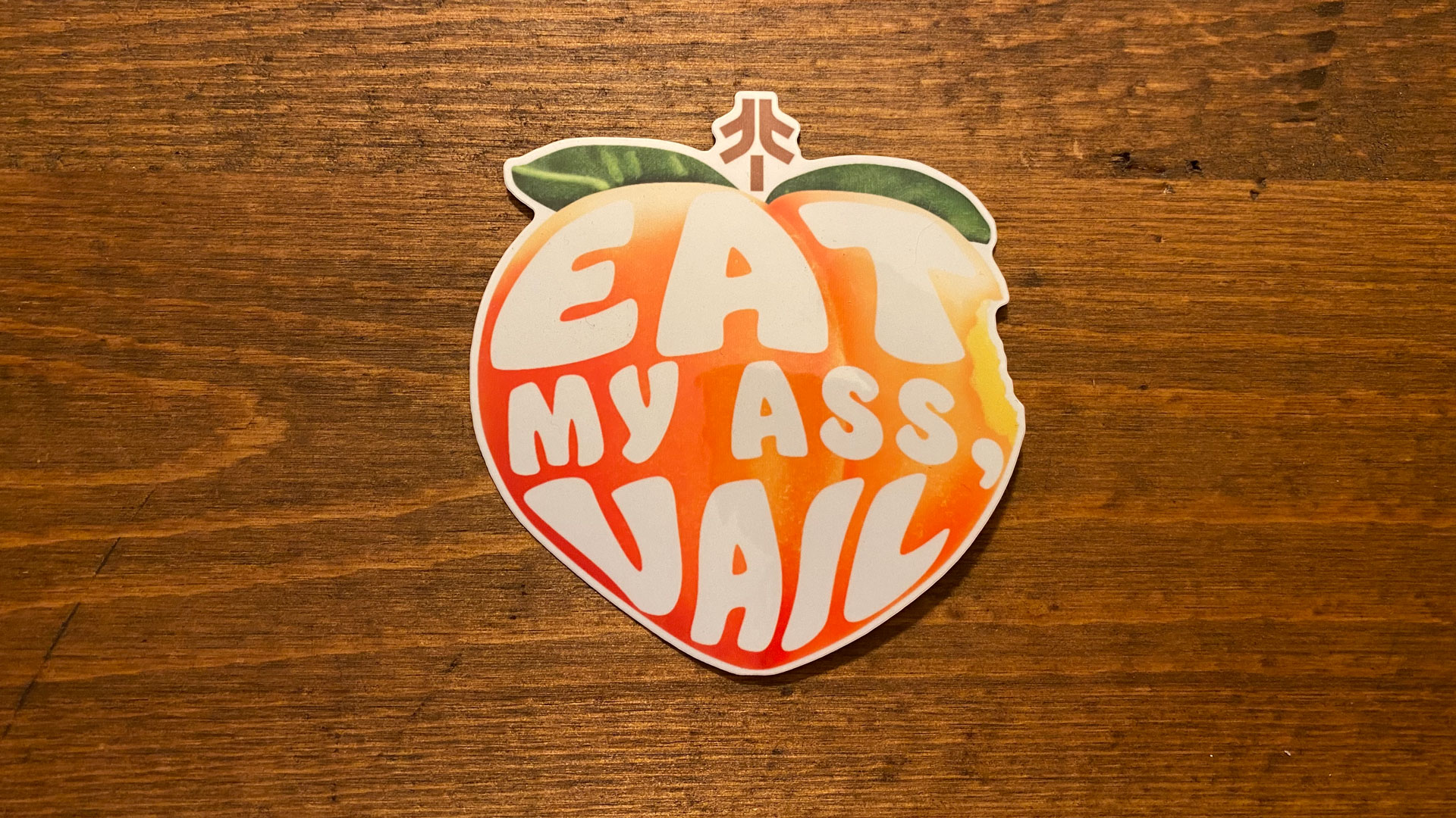Vinyl Sticker with peach emoji graphic and text "Eat My Ass, Vail"
